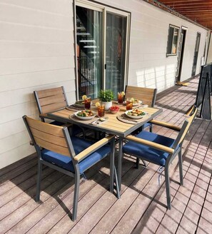 Une terrasse avec une table dressée pour quatre personnes, entourée de chaises dotées de coussins bleus.