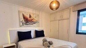A neatly made bed with a headboard, a bedside table, a painting on the wall, and a window with a view. - 504 ocean tower 60m2 sea view 2 quartos (Fortaleza)