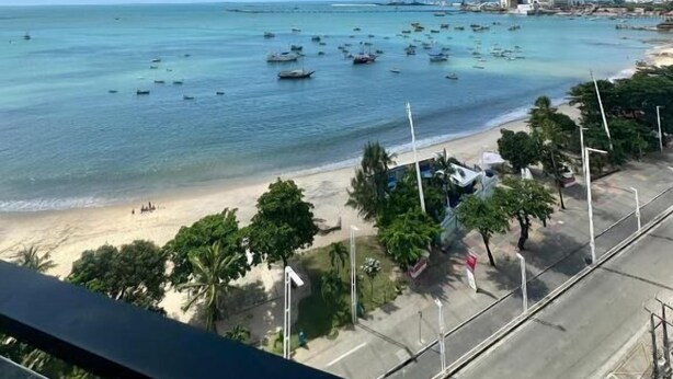 A beach view with boats, clear blue sky, and buildings in the distance. - 504 ocean tower 60m2 sea view 2 quartos (Fortaleza)