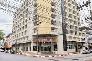 A multi-story hotel with a central entrance, balconies, and a flag.