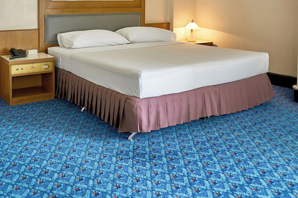 Una habitación de hotel con cama, mesita de noche, lámpara y equipo de aire acondicionado.