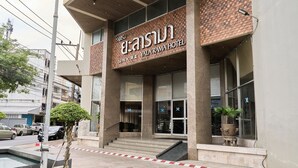A hotel entrance with a brick facade, large windows, and a staircase leading to the entrance.