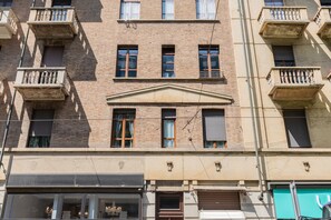 A multi-story building with balconies, a central entrance, and a ground-level shop. - Molinette e Lingotto Studio by Wonderful Italy (Turin)