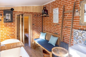 Un baño rústico con un banco de madera, una bañera y un letrero en alemán.