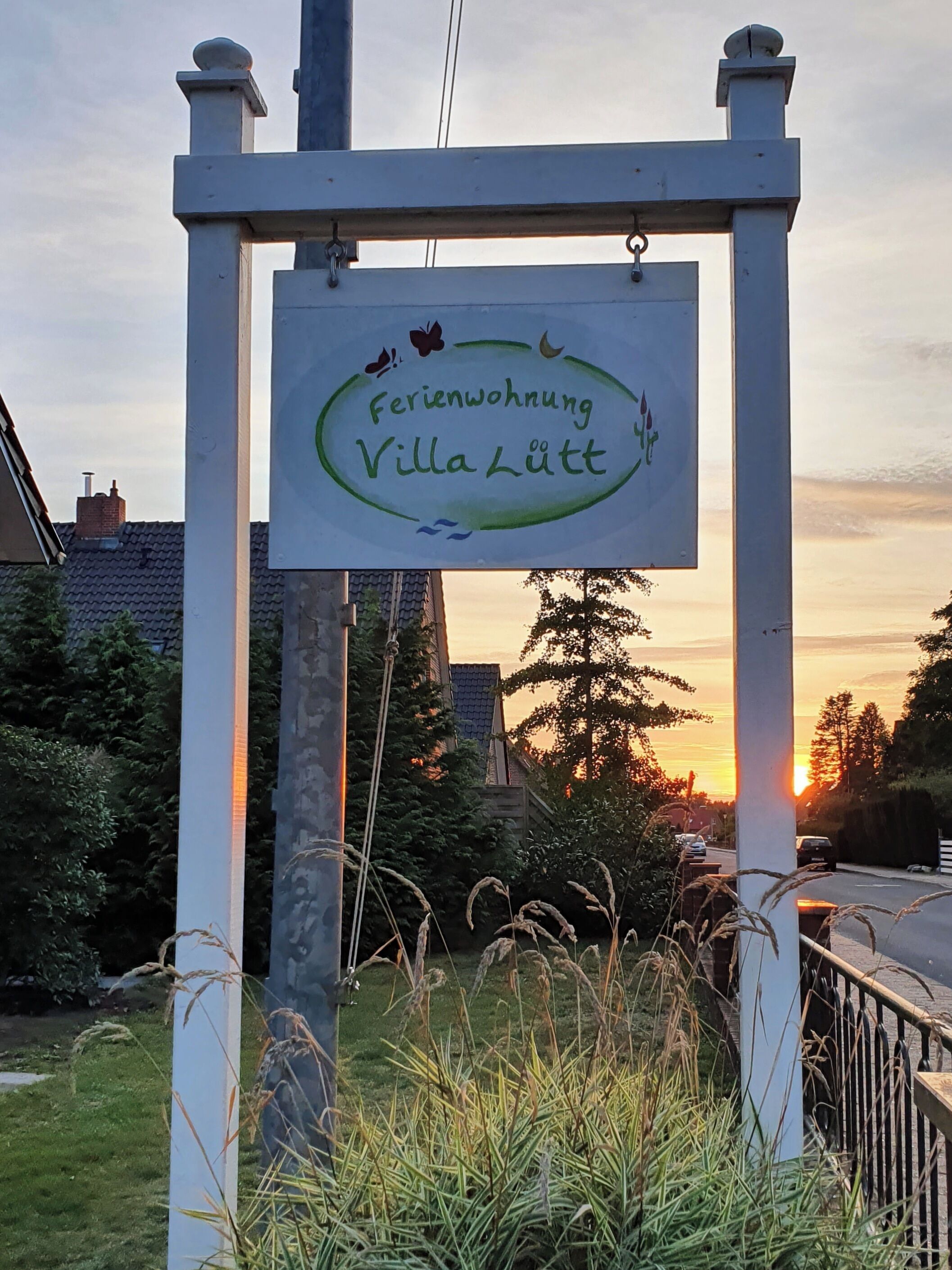 Señal de la propiedad llamada 'Ferienwohnung Villa Lütt', con un marco blanco y un borde ovalado verde.