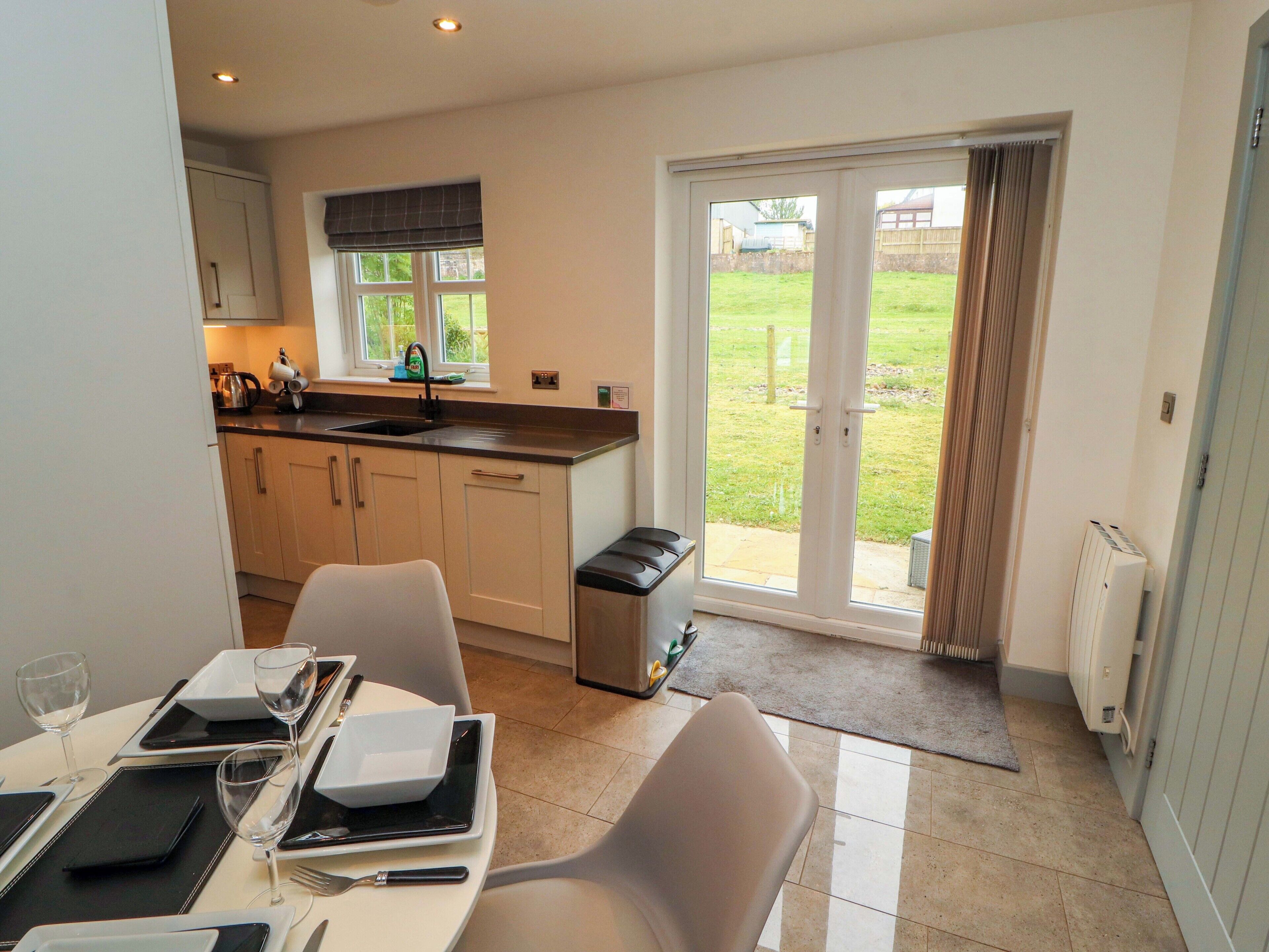 A modern kitchen with a dining area, a large sliding glass door to a garden, and a white radiator.