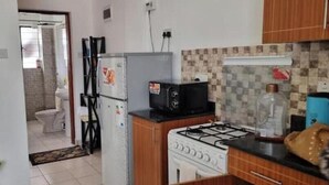 A compact kitchen with a gas stove, a refrigerator, a microwave, and a sink. - Cozy 1-Bedroom Apartment in Westpark Heights (flyover)