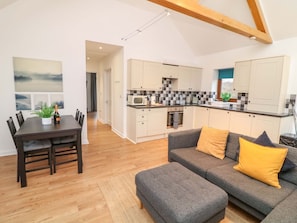A modern kitchen with white cabinets, a microwave, and a dining area with a table and chairs. - Lodge 7, South Hykeham (Lincoln)