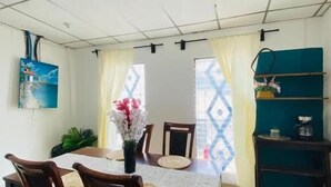 Un comedor con una mesa, sillas y un jarrón de flores.