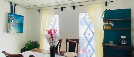 A dining area with a table, chairs, and a vase of flowers.