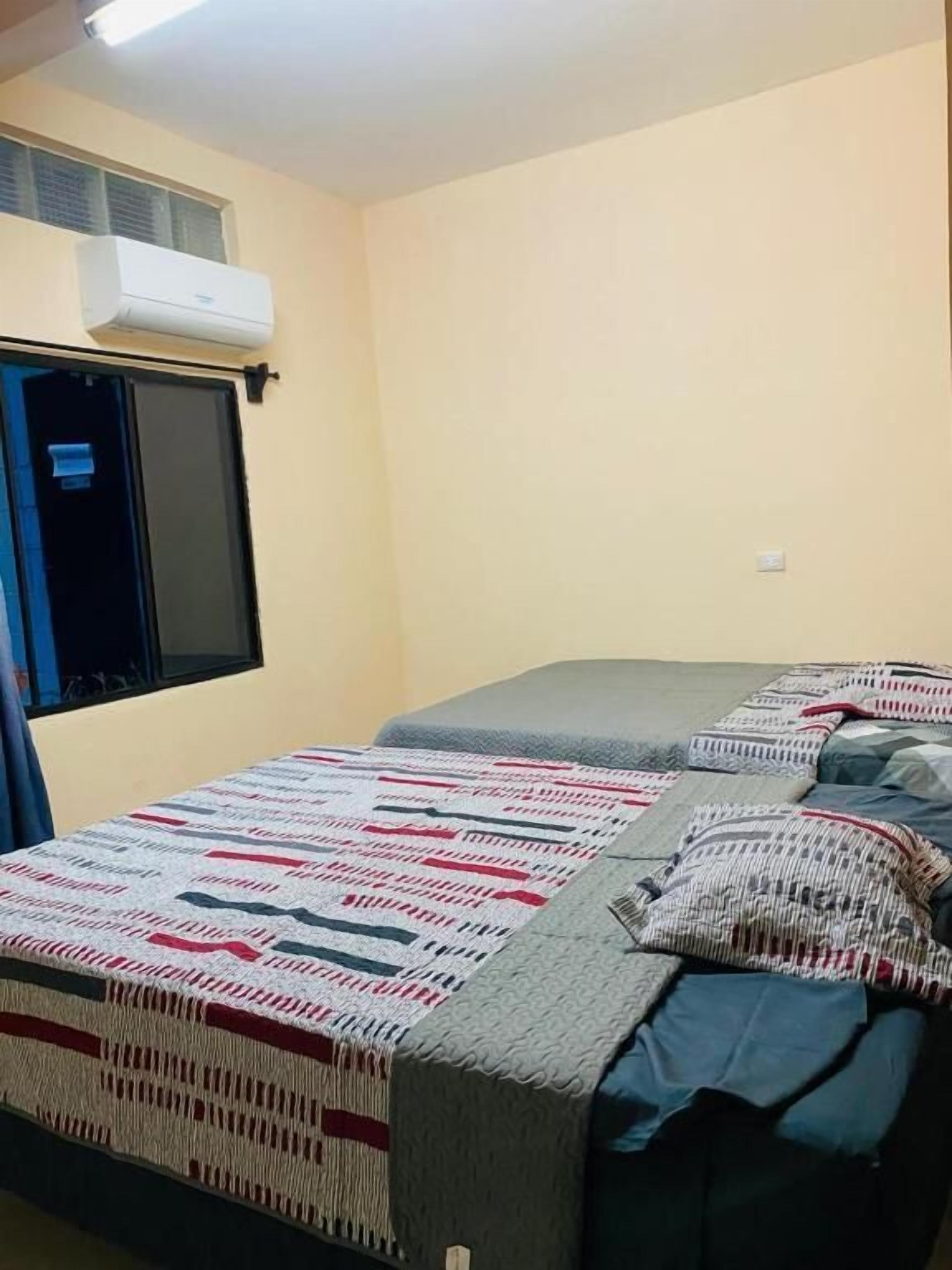 A bedroom with a bed, a window, and an air conditioning unit.