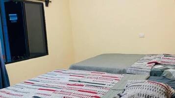 A bedroom with a bed, a window, and an air conditioning unit.