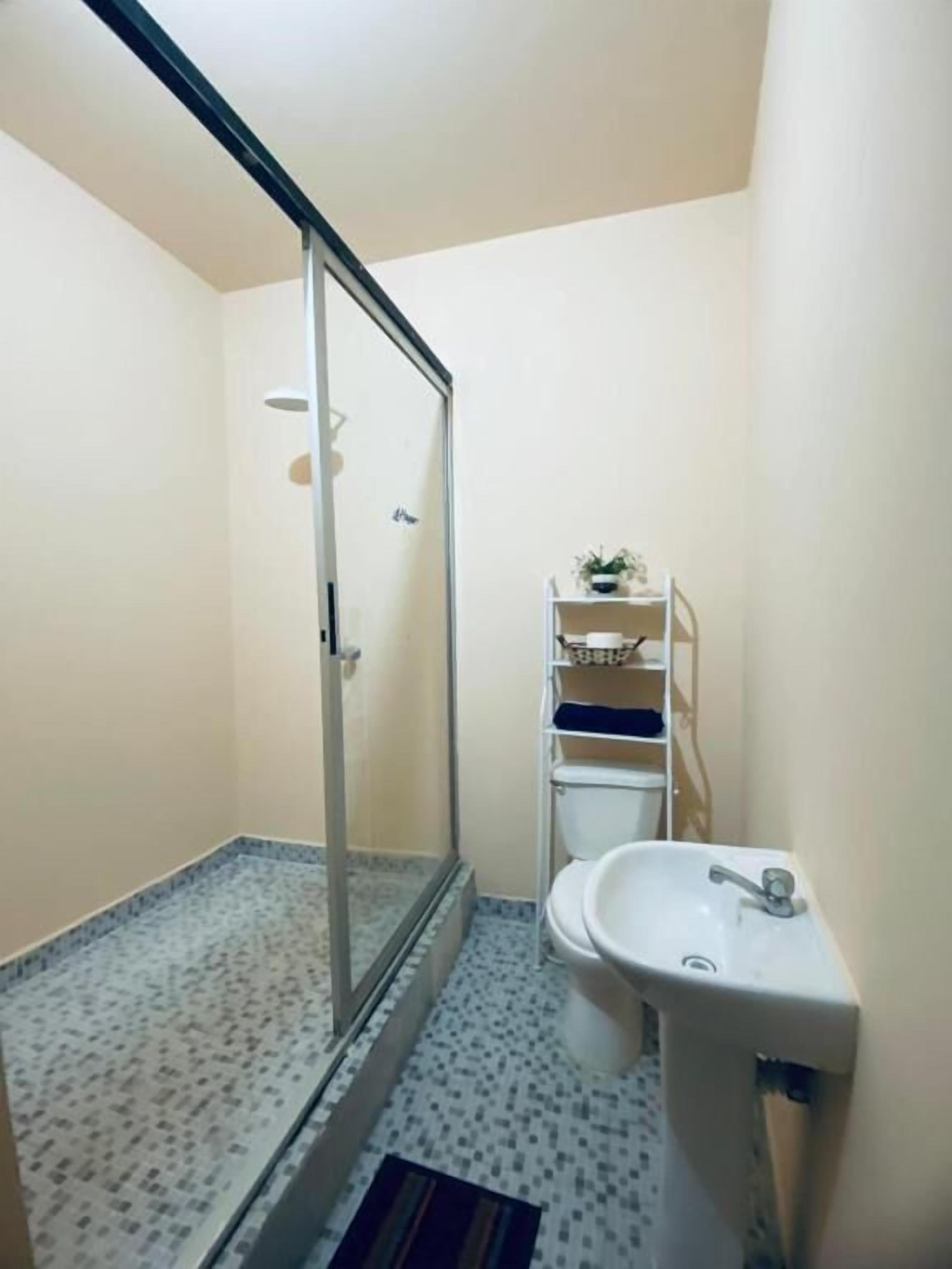 Un baño pequeño con ducha, inodoro y lavamanos.