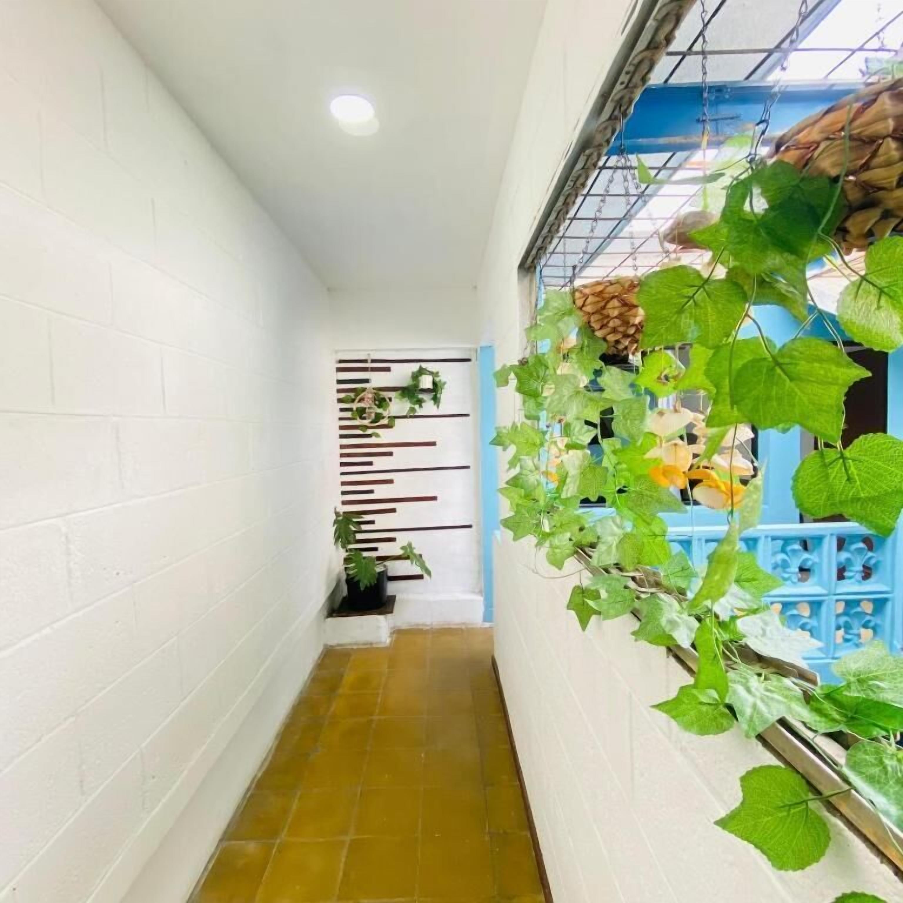 A narrow hallway with white walls, a tiled floor, and a blue railing on the right.