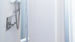 Ein modernes Badezimmer mit Duschkabine aus Glas, einer weißen Toilette und einem Handtrockner an der Wand.