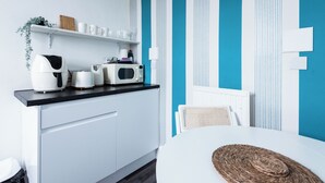 Eine moderne Küche mit weißen Schränken, einer schwarzen Arbeitsplatte und einer blauen Wand mit weißen Streifen.