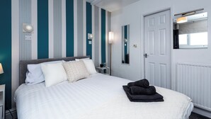 Ein ordentlich eingerichtetes Hotelzimmer mit einem Bett, einem Nachttisch, einem Spiegel und einer Tür.