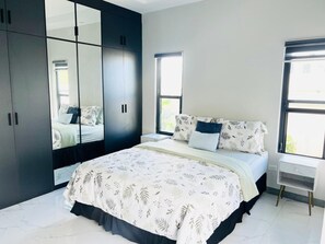 A bedroom with a bed, a wardrobe, a nightstand, and a window. - Beautiful 2-bedroom house with AC in charming St. Ann Parish (St. Ann Parish)