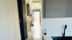 Una cocina moderna con un lavamanos integrado, una botella de agua en la encimera y un pasillo que conduce a otra habitación.
