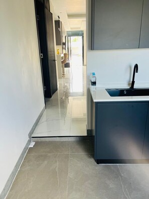 A modern kitchen with a built-in sink, a water bottle on the counter, and a hallway leading to another room. - Beautiful 2-bedroom house with AC in charming St. Ann Parish (St. Ann Parish)