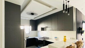 Una cocina moderna con armarios oscuros, una encimera blanca y una isla central con taburetes de bar.