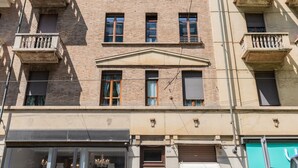 Un edificio a più piani con balconi, un ingresso centrale e un negozio a livello strada.
