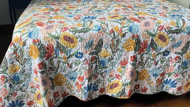 A bed with a floral bedspread, two nightstands with lamps, and a painting on the wall.