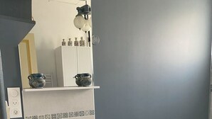 A bathroom with a white sink, cabinets, a mirror, and blue towels on the floor.