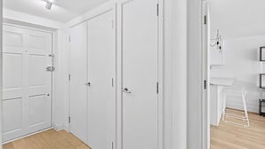 A hallway with white doors, a white drying rack, and a white shelf unit. - Belgravia Living 2-bed, 2-bath Fourth Floor Apartment (London)