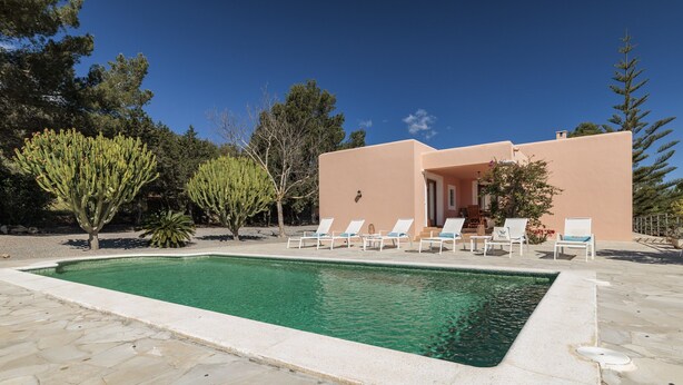 A swimming pool with lounge chairs, a building with a door, and surrounding trees. - Nice Villa in Sant Carles With Pool (Santa Eulalia del Rio)
