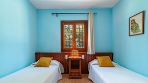 A room with two beds, a window with curtains, a wooden headboard, a wall-mounted lamp, and a framed picture. - Nice Villa in Sant Carles With Pool (Santa Eulalia del Rio)