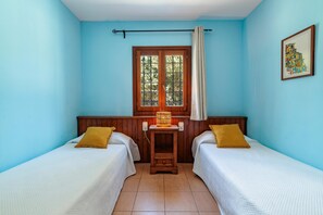 A room with two beds, a window with curtains, a wooden headboard, a wall-mounted lamp, and a framed picture. - Nice Villa in Sant Carles With Pool (Santa Eulalia del Rio)