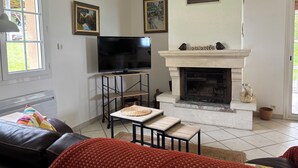 Un salon avec une cheminée, un téléviseur posé sur un meuble et une fenêtre.