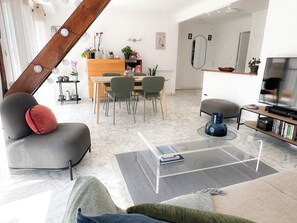 Ein modernes Wohnzimmer mit Sofa, Couchtisch und Essbereich mit Stühlen und einem Holztisch.