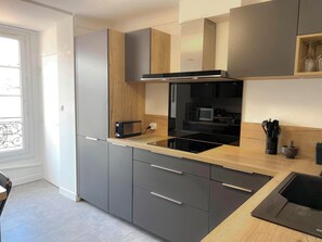 Eine moderne Küche mit grauen Schränken, einem schwarzen Herd, einer Mikrowelle und einem Toaster.