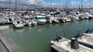 Un port de plaisance où de nombreux bateaux sont amarrés, une jetée en bois et un ciel dégagé.