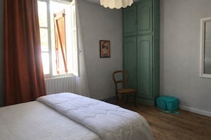 A bedroom with a bed, a chair, a wardrobe, and a window with curtains. - Pleasant little house located in the Pyrenees National Park. (Pierrefitte-Nestalas)