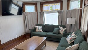 A living room with a green sofa, a wooden coffee table, and a TV mounted on the wall. - 3-bedroom Cozy Home Close to Santa Claus, IN and Holiday World (Ferdinand)
