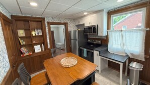 A compact kitchen with a dining table, chairs, a microwave, refrigerator, and a stove. - 3-bedroom Cozy Home Close to Santa Claus, IN and Holiday World (Ferdinand)