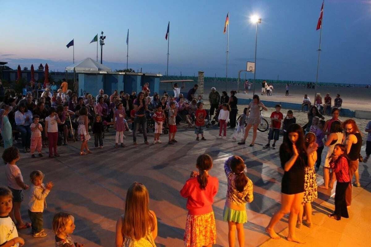 A crowded outdoor area with people, a tent, and flags.