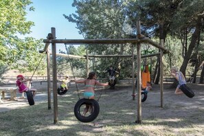 Children playing on a playground with swings and tire swings.