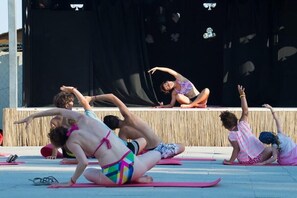 A group of people practicing yoga outdoors on mats.