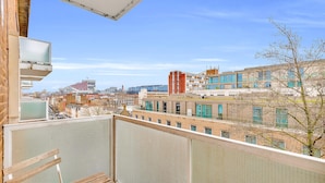 Een balkon met uitzicht op een stadsgezicht, inclusief gebouwen en een boom.