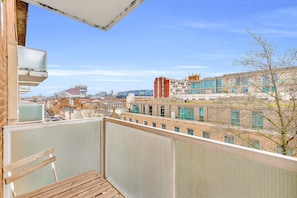 Ein Balkon mit Blick auf eine Stadtlandschaft, einschließlich Gebäude und eines Baumes.