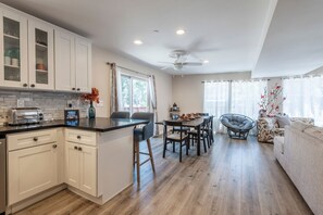 A modern kitchen with white cabinets, a central island, and a dining area with a round table and chairs. - Lakeview Cabin w/Walk to Lake + Slopes + Dog (Big Bear Lake)