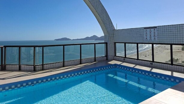 En swimmingpool med udsigt til havet og en strand.
