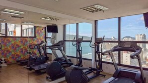 Et fitnessrum med løbebånd, crosstrainere og en spejlvæg.