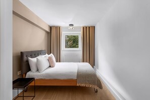 Ein Schlafzimmer mit Bett, Fenster, Heizkörper und Nachttisch.