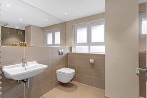 A bathroom with a white sink, toilet, and a window with frosted glass. - Belgravia Living First Floor 2-bed With Balcony (London)
