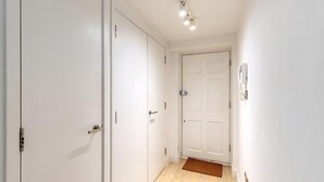 A hallway with white doors, a light switch, and a doormat. - Belgravia Living 2-bed, 2-bath Home With Balcony (London)